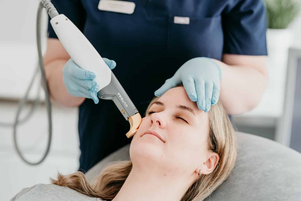 An aesthetician performing laser treatment on a client with skin rejuvenation